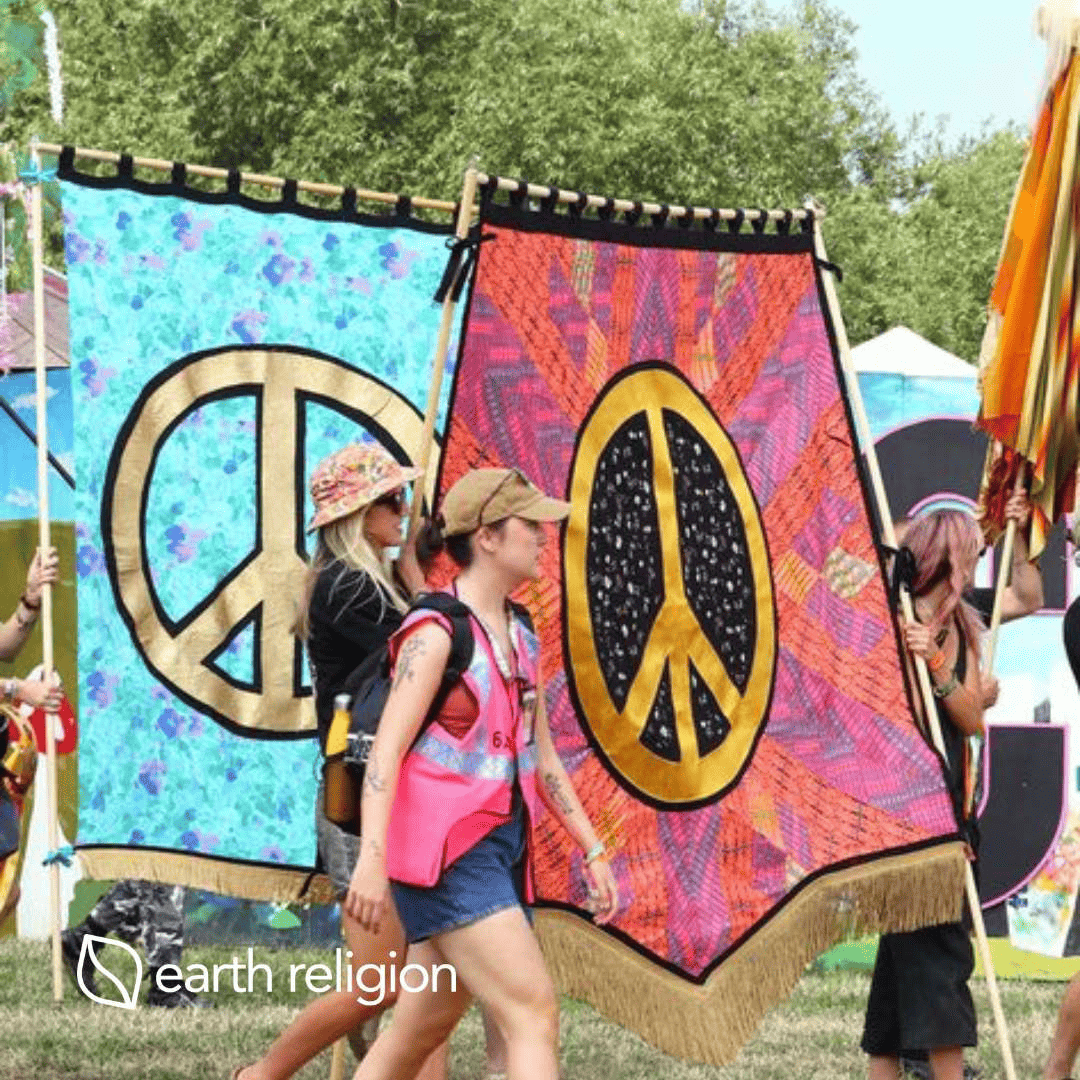 A woman walking around a festival or peace movement with peace tapestry's flying behind her.